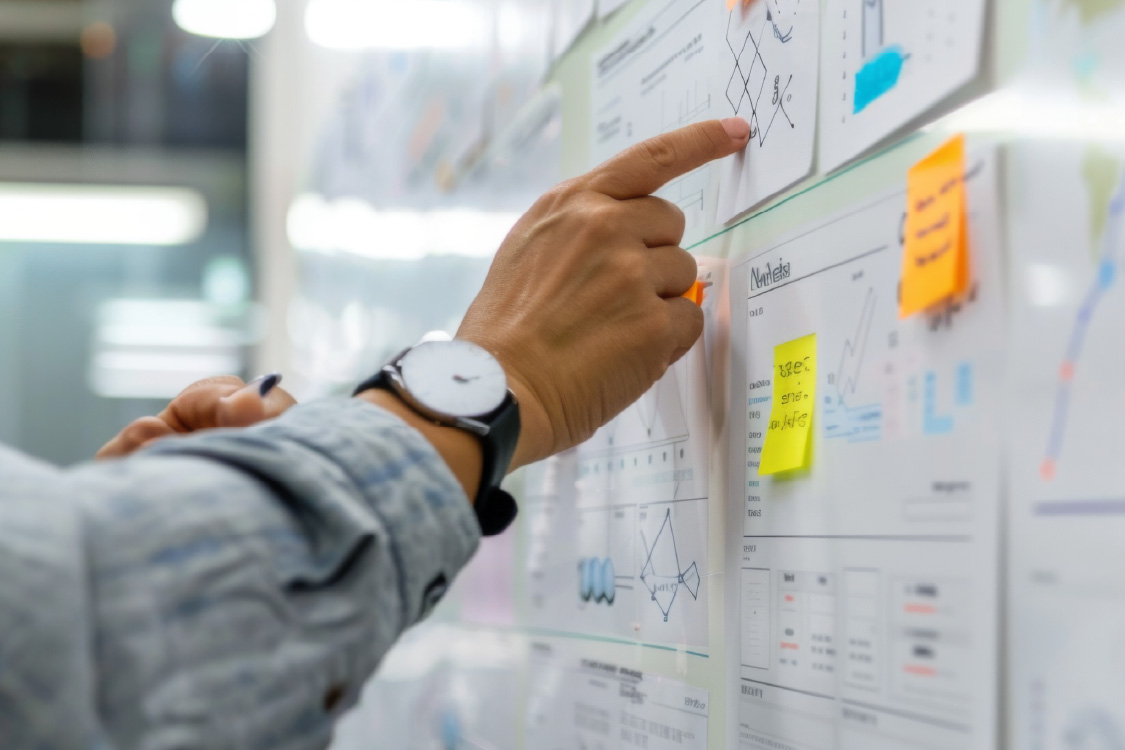 Man's hand pointing at a whiteboard with notes in a corporate office