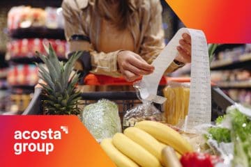 Woman reviews her store receipt while standing by her grocery cart in a supermarket aisle.