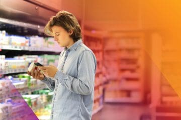 Gen Z shopper considers a product in a retail store while using AI on his phone